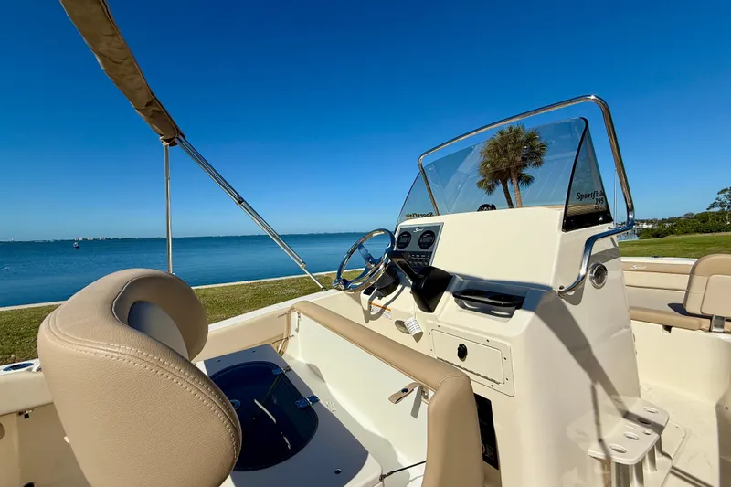 Slide: The Image of 2026 Scout 195 Sportfish boat interior with steering wheel, beige seating, and clear blue sky backdrop. - 14