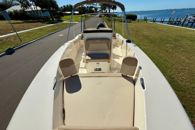 Slide: The Image of 2026 Scout 195 Sportfish boat with beige seating, parked near waterfront. - 22