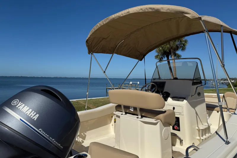 Slide: The Image of 2026 Scout 195 Sportfish boat with Yamaha engine, beige interior, and canopy on a sunny day. - 6