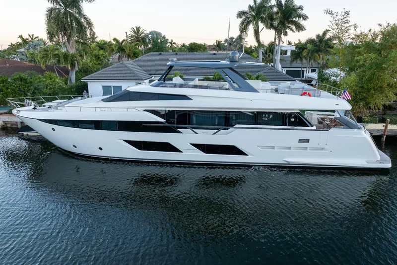 The Image of 2021 Ferretti Yachts 920 luxury yacht docked by palm trees and waterfront home. - 1
