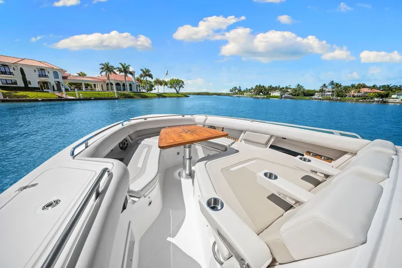 Slide: The Image of The image shows the bow of a 2026 Boston Whaler 380 Realm with luxurious seating and a wooden table. - 22