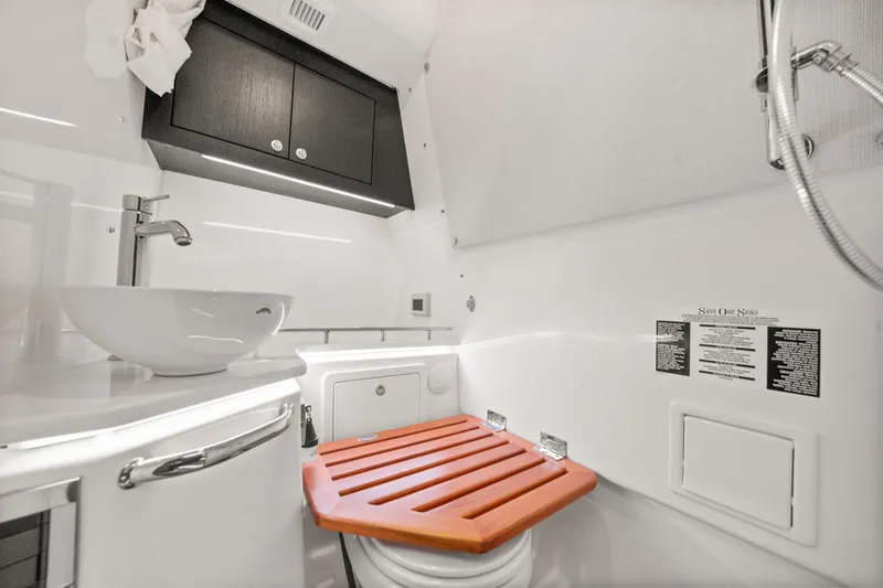 Slide: The Image of The image shows a modern boat bathroom with a sink, shower, and wooden seat. - 31