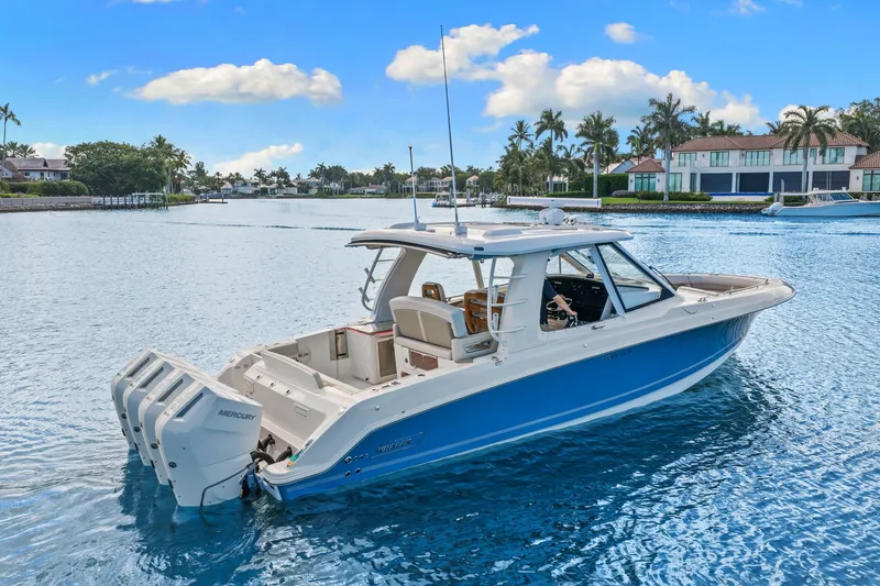 Slide: The Image of A 2026 Boston Whaler 380 Realm on calm water. Palm trees and houses in the background. - 15