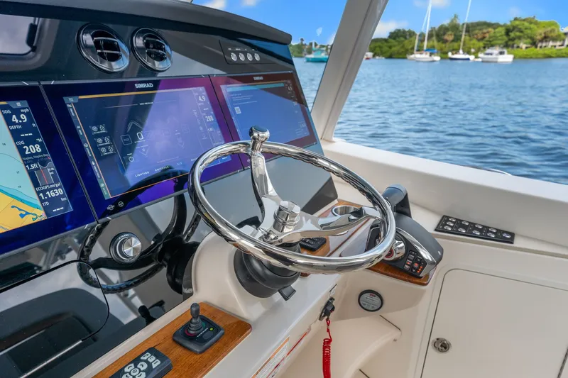 Slide: The Image of Helm of the Boston Whaler 380 Realm with modern navigation systems and a sleek steering wheel. - 38