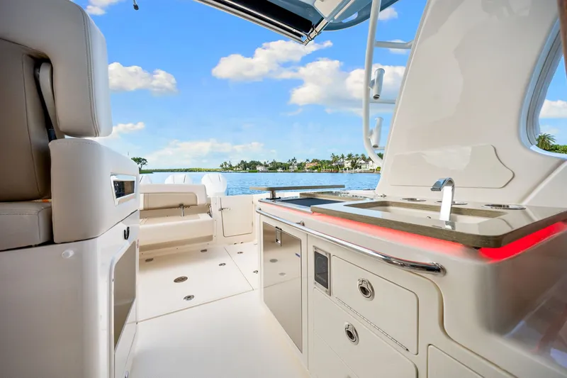 Slide: The Image of Boston Whaler 380 Realm 2026: Luxurious cockpit with sink and seating area, set against a scenic water backdrop. - 46