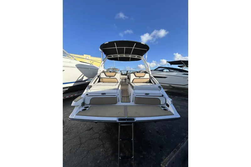 Slide: The Image of 2021 Yamaha Boats 275SE with sleek design and spacious seating, docked under a clear blue sky. - 4