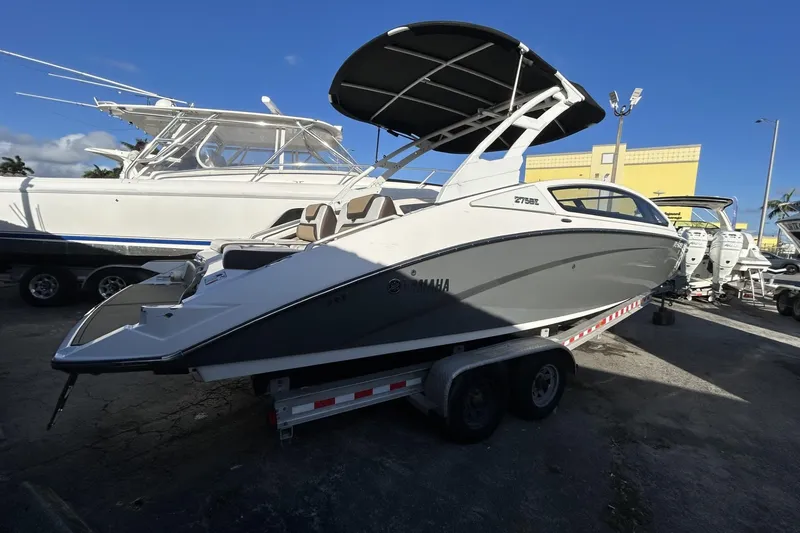 Slide: The Image of 2021 Yamaha Boats 275SE on trailer, sleek design, parked outdoors under clear blue sky. - 5