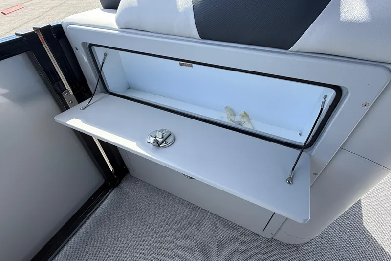 Slide: The Image of 2026 Avalon 2385 LSZ Tri Toon boat storage compartment with open lid and latch. - 15