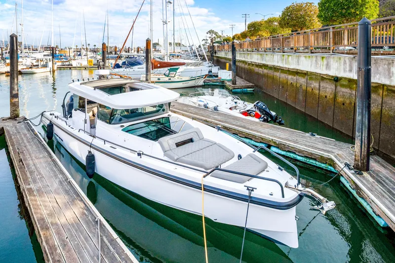 Slide: The Image of 2021 Axopar 37 XC Cross Cabin docked in a marina, surrounded by boats. - 2