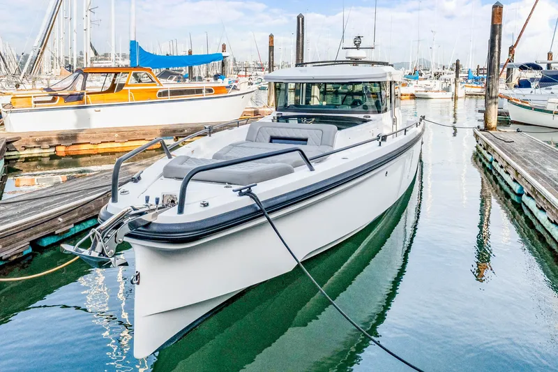 Slide: The Image of 2021 Axopar 37 XC Cross Cabin boat docked in a marina, surrounded by other vessels. - 5