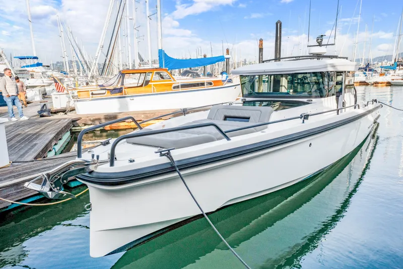 Slide: The Image of 2021 Axopar 37 XC Cross Cabin boat docked at a marina, surrounded by other vessels. - 6