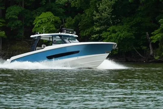 Slide: The Image of 2021 Boston Whaler 420 Outrage cruising on a lake with lush green trees. - 10