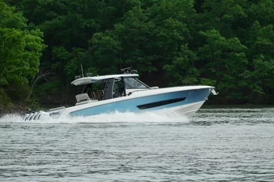 Slide: The Image of 2021 Boston Whaler 420 Outrage cruising on a lake with lush green trees. - 11