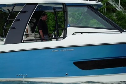 Slide: The Image of 2021 Boston Whaler 420 Outrage boat on water, side view with blue and white exterior. - 4