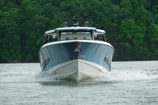 Slide: The Image of 2021 Boston Whaler 420 Outrage cruising on a lake with lush green forest backdrop. - 6