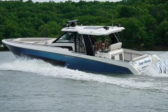 Slide: The Image of 2021 Boston Whaler 420 Outrage cruising on a lake with lush green trees. - 9