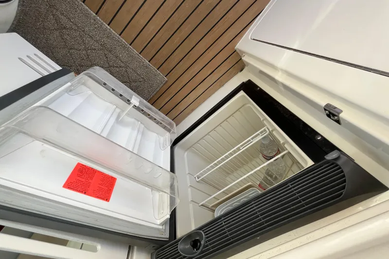 Slide: The Image of Open refrigerator on 2003 Searay 380 boat, showing empty shelves and water bottles. - 16