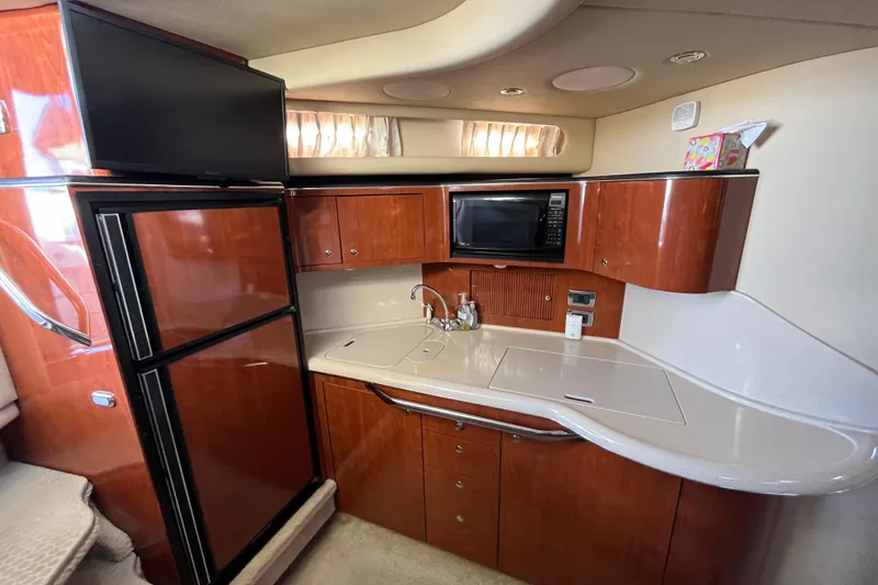 Slide: The Image of 2003 Searay 380 yacht kitchen with wood cabinets, microwave, and refrigerator. - 23
