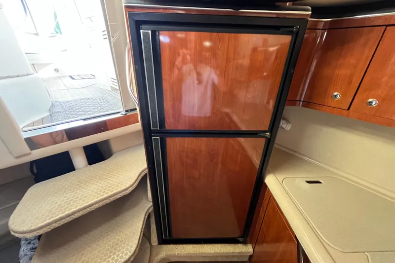 Slide: The Image of 2003 Searay 380 yacht interior with wooden cabinetry and compact refrigerator. - 24