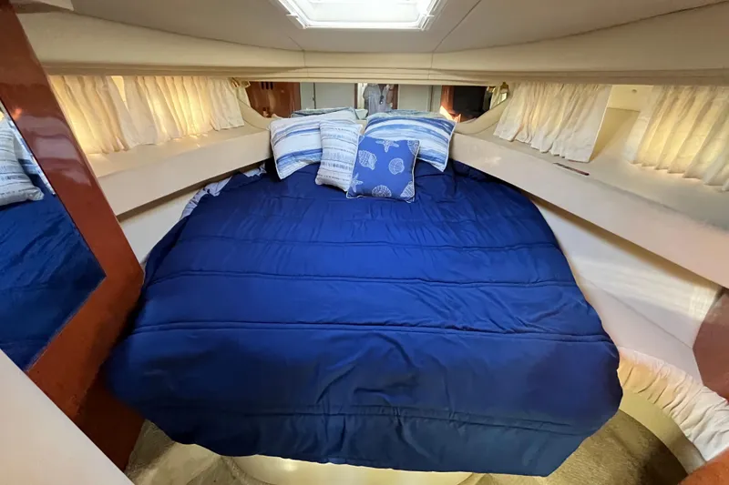Slide: The Image of 2003 Searay 380 boat cabin with blue bedding and decorative pillows. - 34