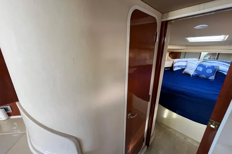 Slide: The Image of Interior cabin of 2003 Searay 380 yacht with blue bedding and wooden door. - 38