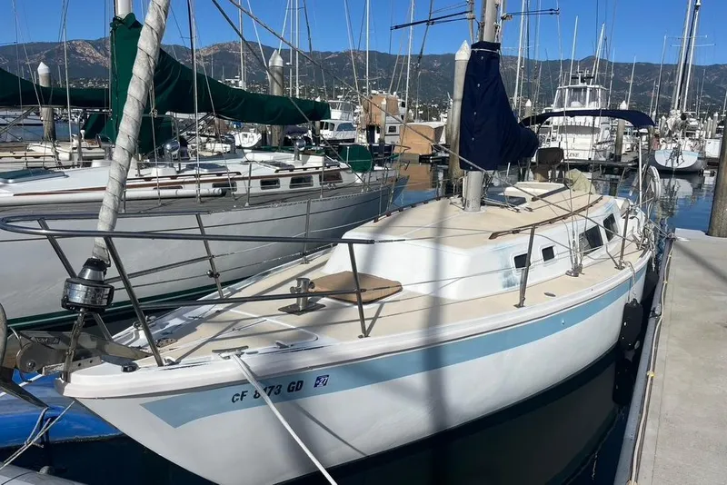 The Image of 1978 CAL 34 sailboat docked in marina, surrounded by other boats, with scenic mountain backdrop. - 1