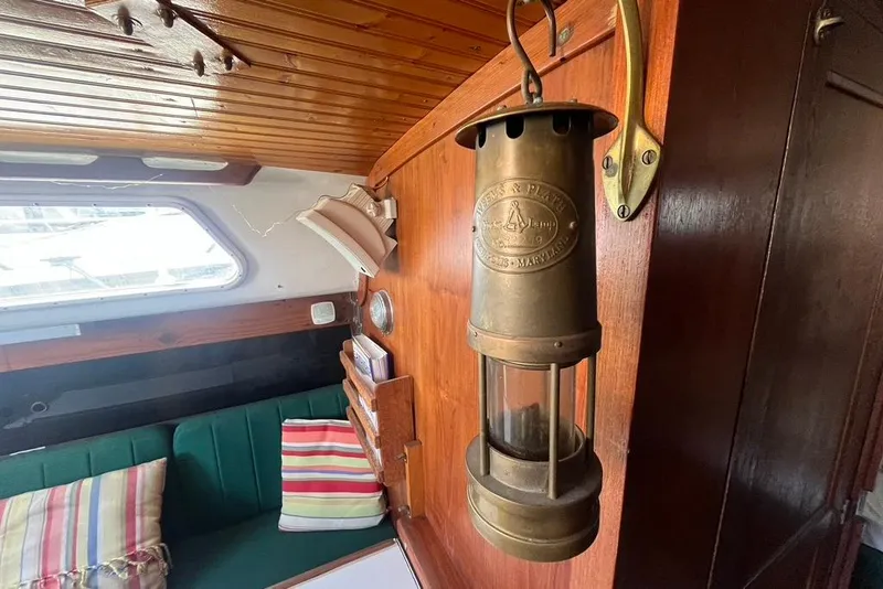 Slide: The Image of Vintage brass lantern in a 1978 CAL 34 sailboat interior with striped cushions. - 11