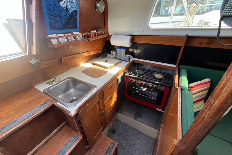 Slide: The Image of Cozy 1978 CAL 34 sailboat interior with kitchen, stove, and seating area. - 6