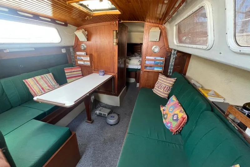 Slide: The Image of Interior of a 1978 CAL 34 sailboat with green seating and colorful pillows. - 9