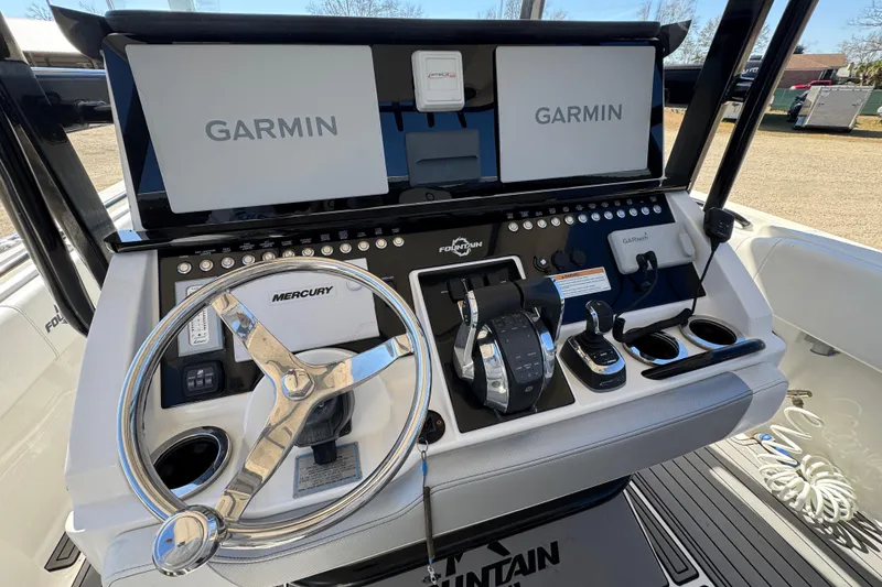 Slide: The Image of 2019 Fountain 34 Center Console boat dashboard with Garmin displays and Mercury steering wheel. - 16