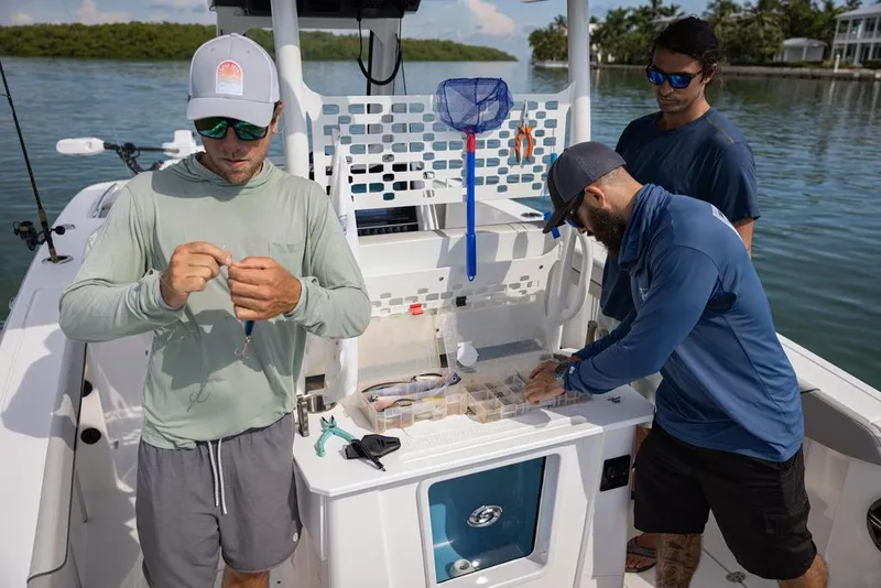 Slide: The Image of Three people preparing fishing gear on a 2026 Hurricane Center Console 24 OB boat. - 15