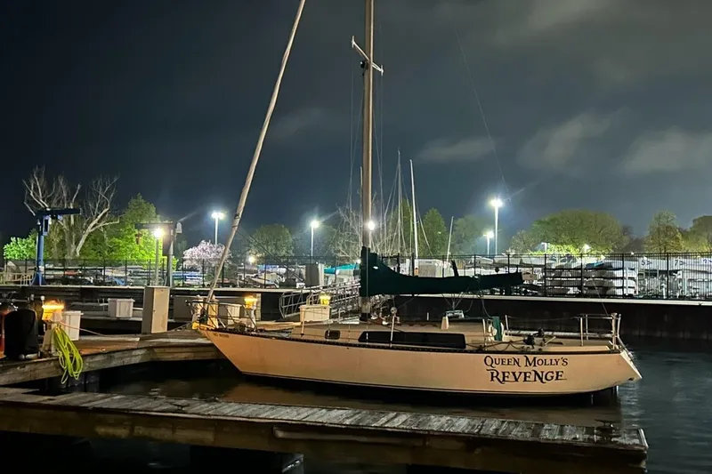 Slide: The Image of 1978 Kettenburg 32 sailboat docked at night, named "Queen Molly's Revenge." - 2