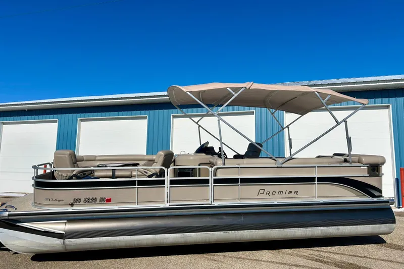 Slide: The Image of 2007 Premier 250 Intrigue pontoon boat with canopy, parked near blue building. - 3