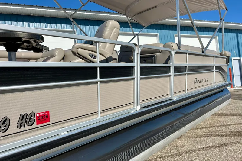 Slide: The Image of 2007 Premier 250 Intrigue pontoon boat with canopy, parked near blue building. - 46