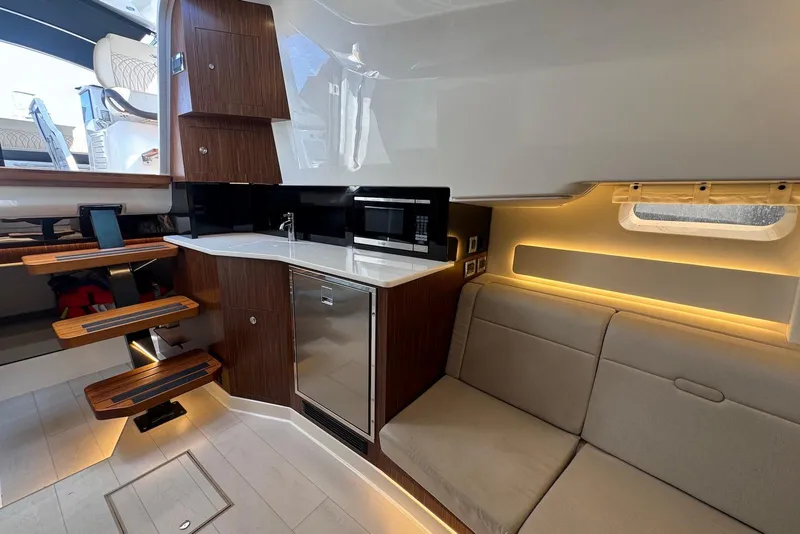 Slide: The Image of 2022 Sea Ray Sundancer 370 Outboard interior with kitchenette, sofa, and modern lighting. - 20