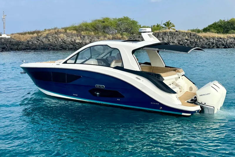 Slide: The Image of 2022 Sea Ray Sundancer 370 Outboard cruising on clear blue water near rocky shoreline. - 3
