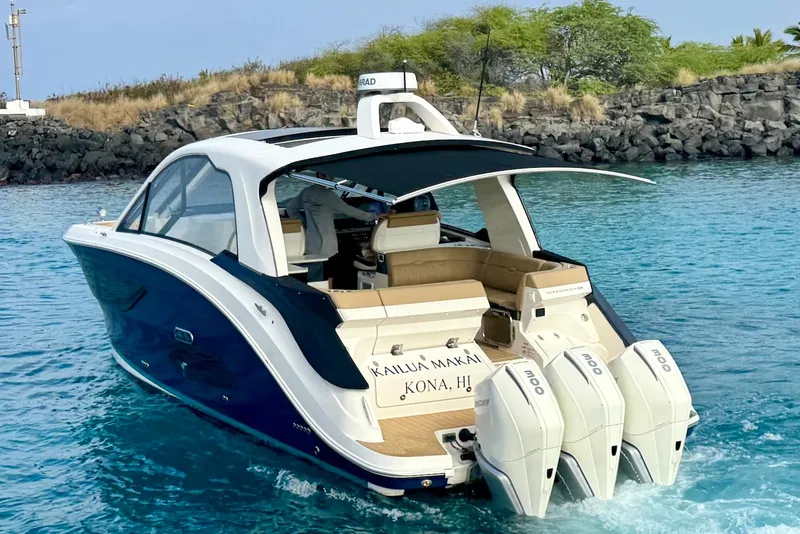 Slide: The Image of 2022 Sea Ray Sundancer 370 Outboard cruising in clear blue waters near rocky shoreline. - 4