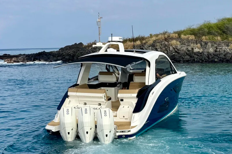 Slide: The Image of 2022 Sea Ray Sundancer 370 Outboard cruising in clear blue waters near rocky shoreline. - 5