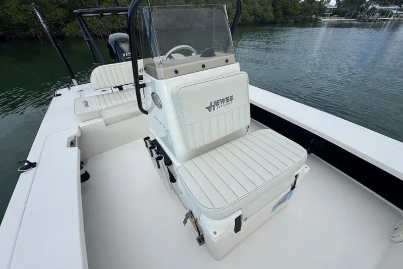 Slide: The Image of 2018 Hewes Redfisher 18 boat interior with seating and console, near water. - 9