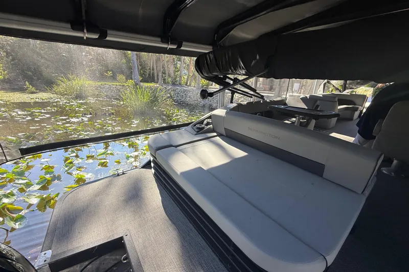 Slide: The Image of 2024 Bennington L Line pontoon boat interior with seating, overlooking a serene water view. - 12