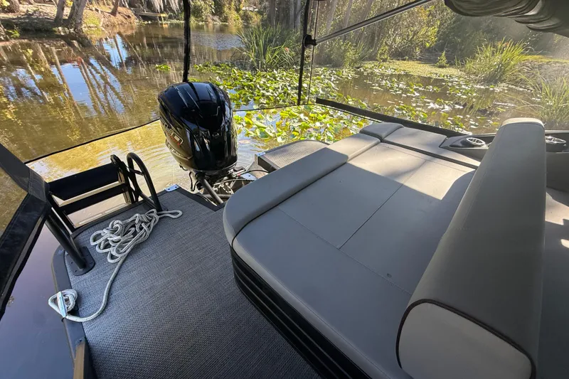 Slide: The Image of 2024 Bennington L Line boat interior with motor, docked by a serene, lily-covered waterway. - 14