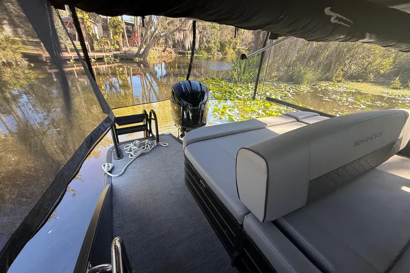 Slide: The Image of 2024 Bennington L Line boat interior with scenic lake view and lush greenery. - 15