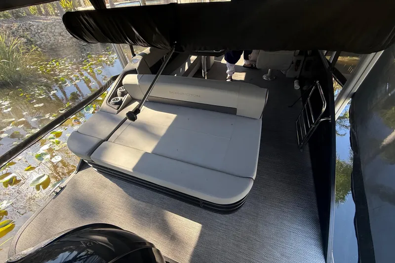 Slide: The Image of 2024 Bennington L Line boat interior with seating and cup holders, near water with lily pads. - 17