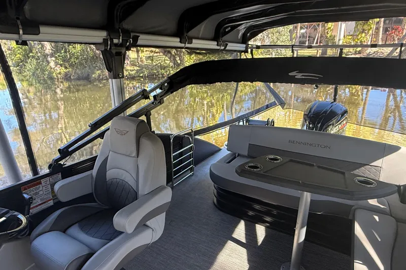 Slide: The Image of 2024 Bennington L Line boat interior with seating and table on a calm waterway. - 19