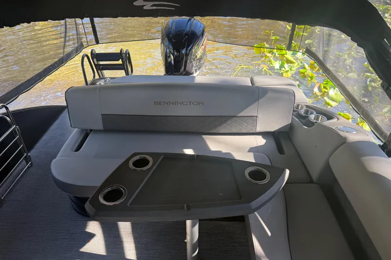 Slide: The Image of 2024 Bennington L Line boat interior with seating and table on a sunny day. - 29