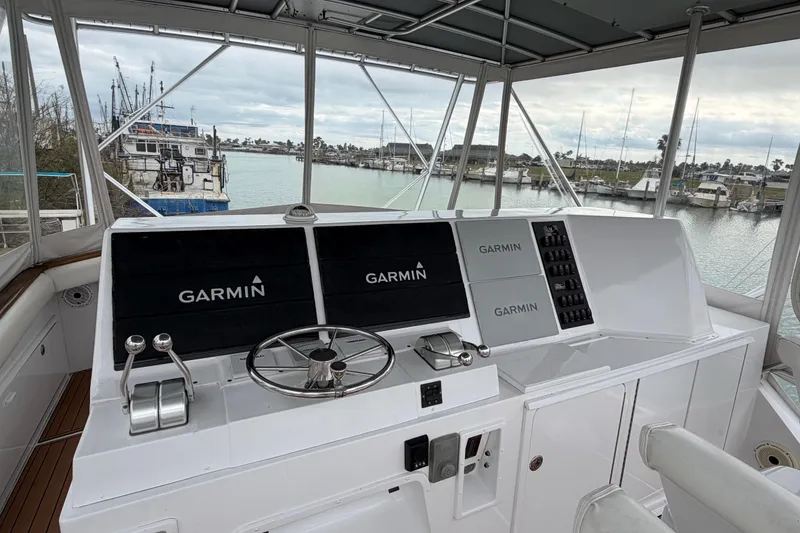 Slide: The Image of 1985 Bertram 54 Convertible yacht helm with Garmin navigation, overlooking marina. - 10