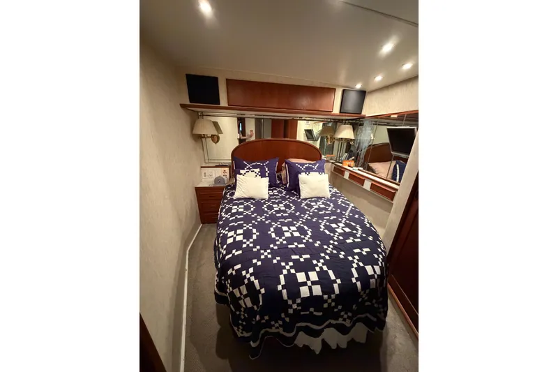 Slide: The Image of 1985 Bertram 54 Convertible yacht bedroom with patterned bedding and cozy lighting. - 32