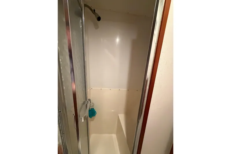 Slide: The Image of Shower area inside 1985 Bertram 54 Convertible yacht, featuring glass door and white interior. - 40