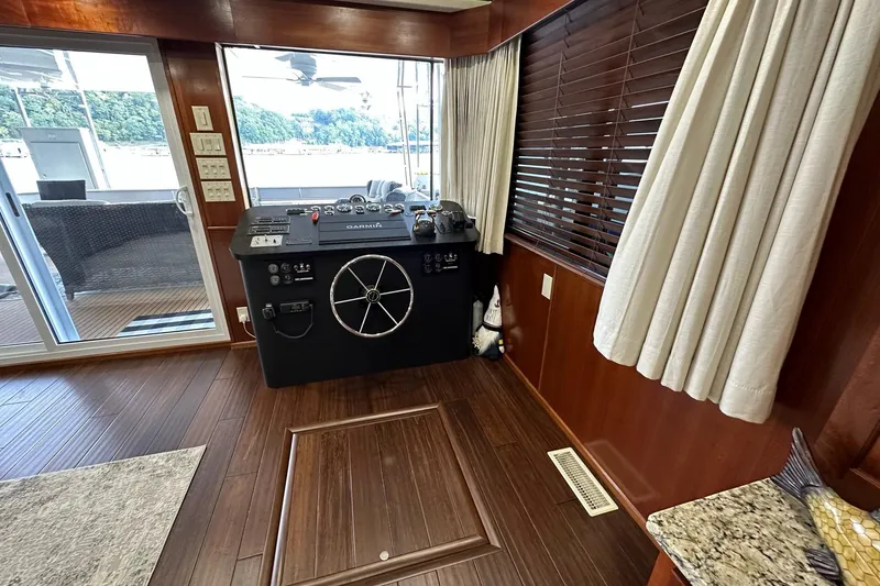 Slide: The Image of 2022 Trifecta houseboat interior with steering console, wooden flooring, and large windows. - 12