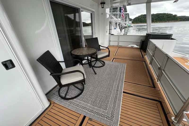 Slide: The Image of 2022 Trifecta houseboat deck with chairs, table, and scenic lake view. - 41